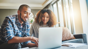 Couple in their 30s looking at their finances on a laptop